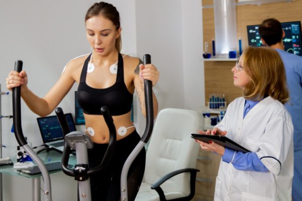 Female athlete doing physical effort on the stepper and the doctor follows her